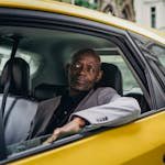 Middle aged African American male in business suit looking away while going by taxi